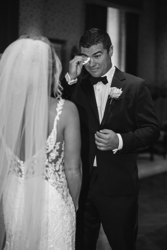 groom wipes tears from his eye after seeing his bride for the first time in the Detroit Athletic Club