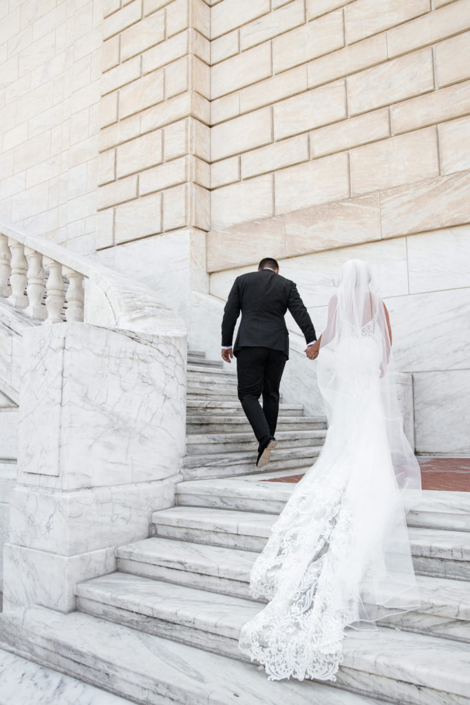 bride and groom walk up the stairs of the Detroit Institute of Arts on their wedding day 