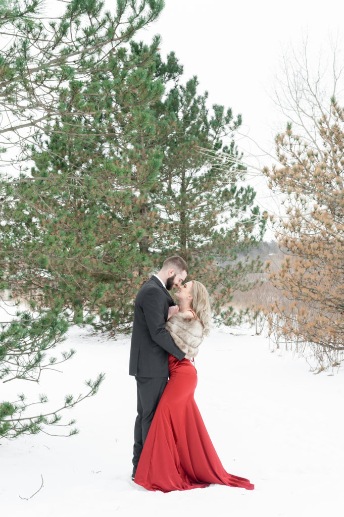 man and woman couple chest to chest in fancy clothes smiling at each other during their winter Grand Rapids engagement session