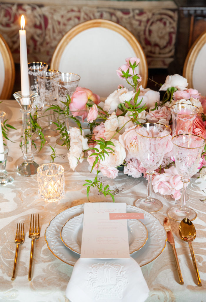luxury wedding reception table with pink and white flowers, gold silverware and white monogram linen