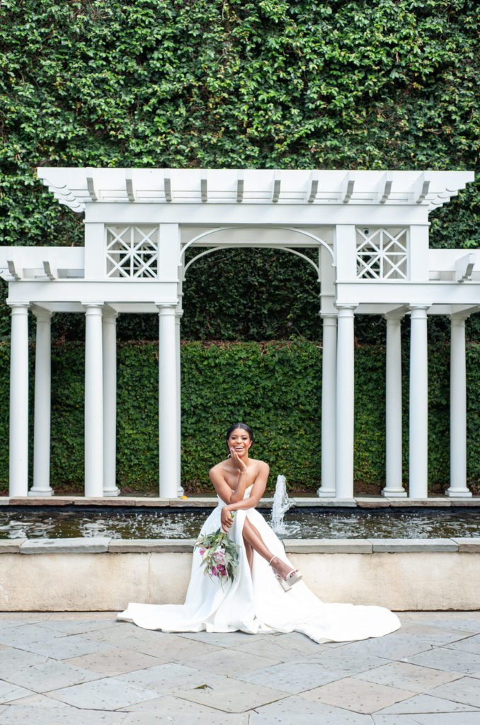 bride sitting on the fountain at the William Aiken House in Charleston South Carolina