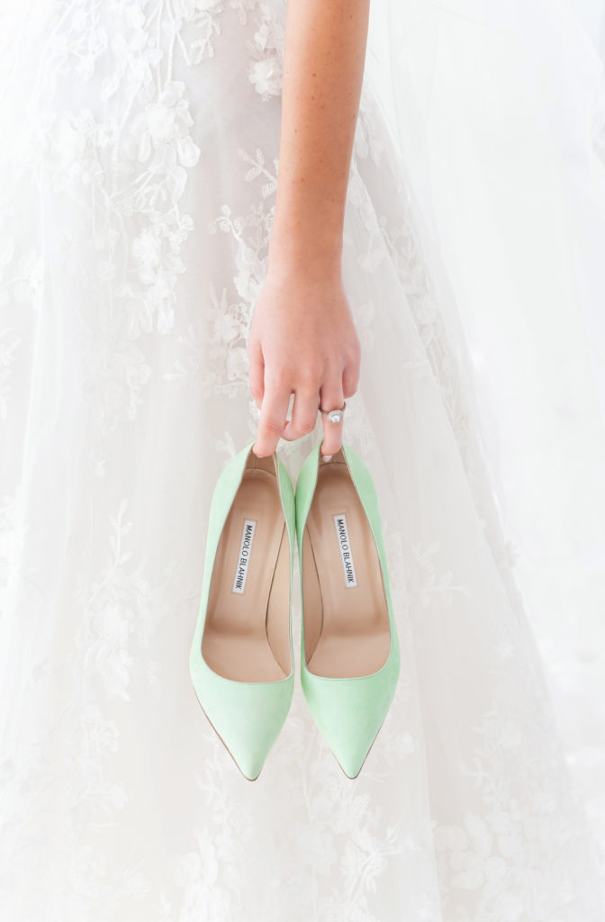 bride holding a pair of green manolo blahnik heels on her wedding day