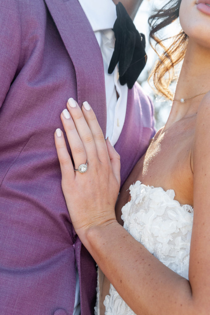 circular wedding ring resting on a groom's purple suit coat