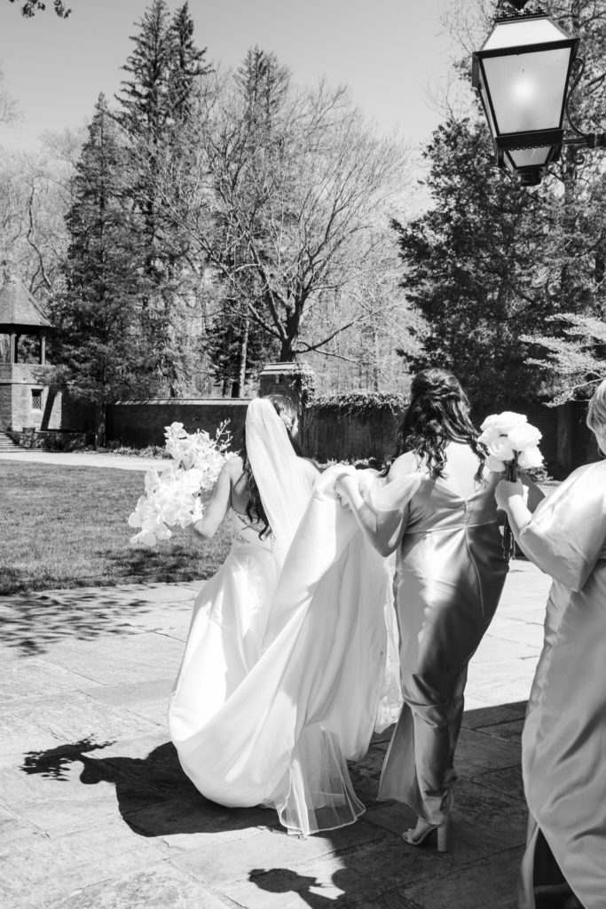 bridesmaids holding the bride's dress as they walk