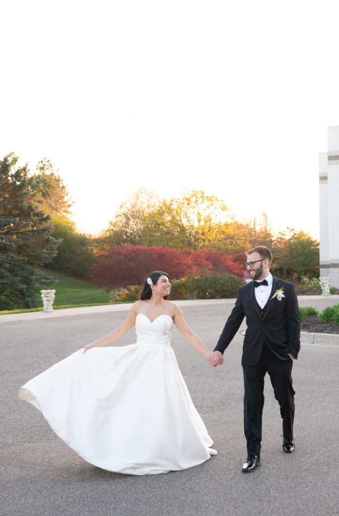 bride and groom holding hands and walking during sunset
