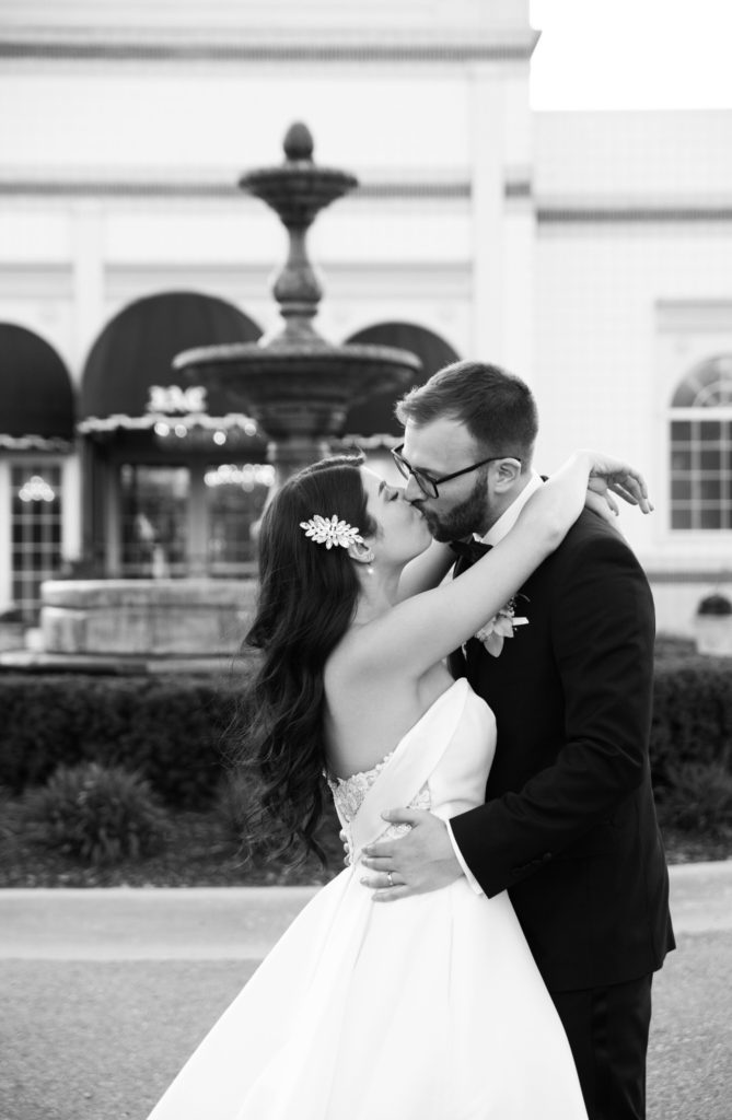 bride and groom kissing in front of a water fountain