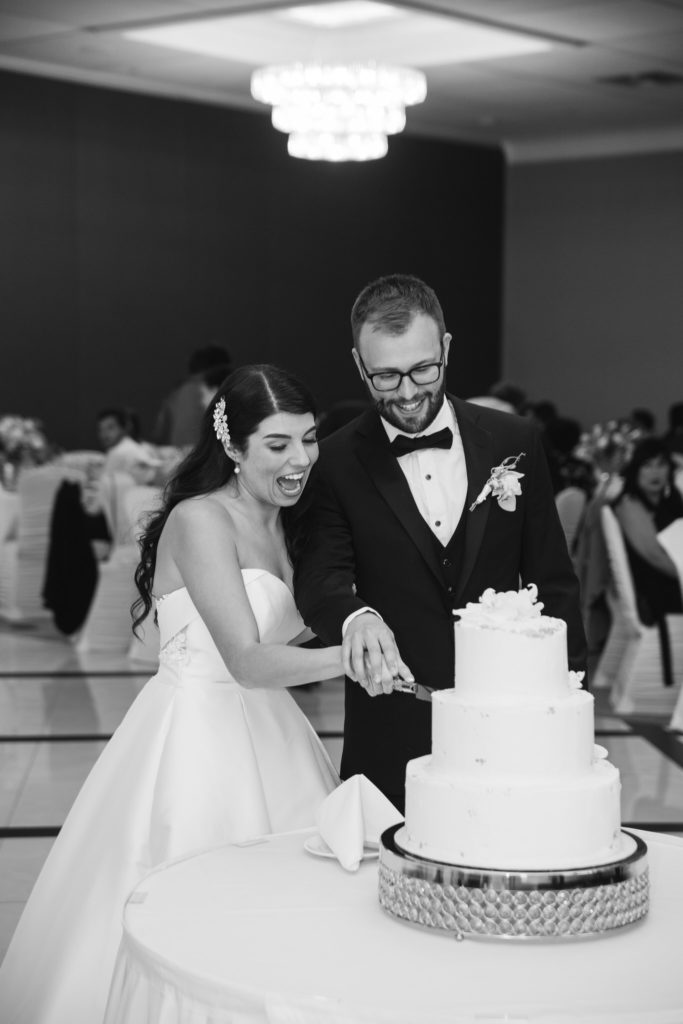 bride and groom cutting into their 3 tier white wedding cake