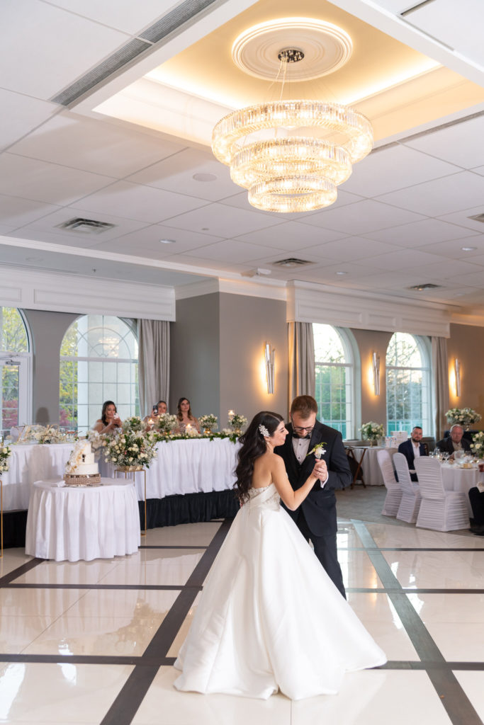 bride and groom's first dance under a golden chandelier 