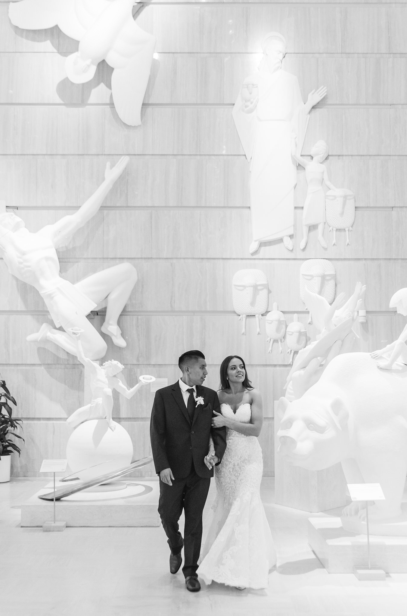 bride and groom holding hands and walking through an art museum in Bay City Michigan