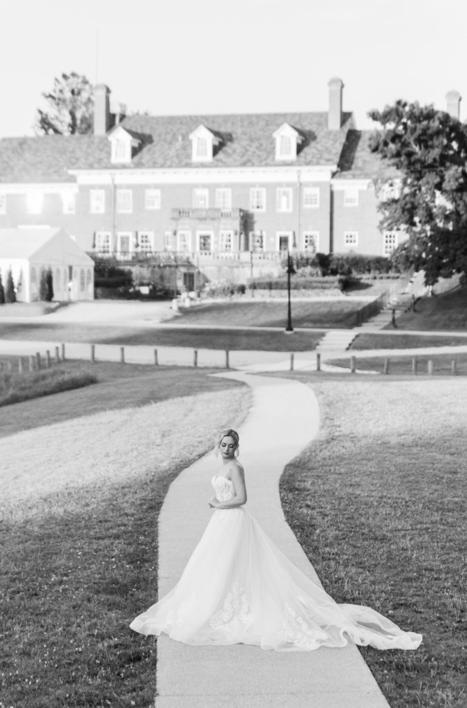 bride holding her hands and looking down with the Felt Mansion in the background 