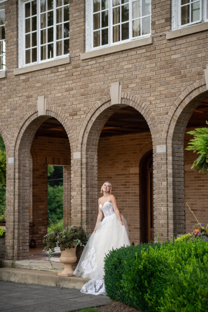 bride smiling upwards under a brick archway