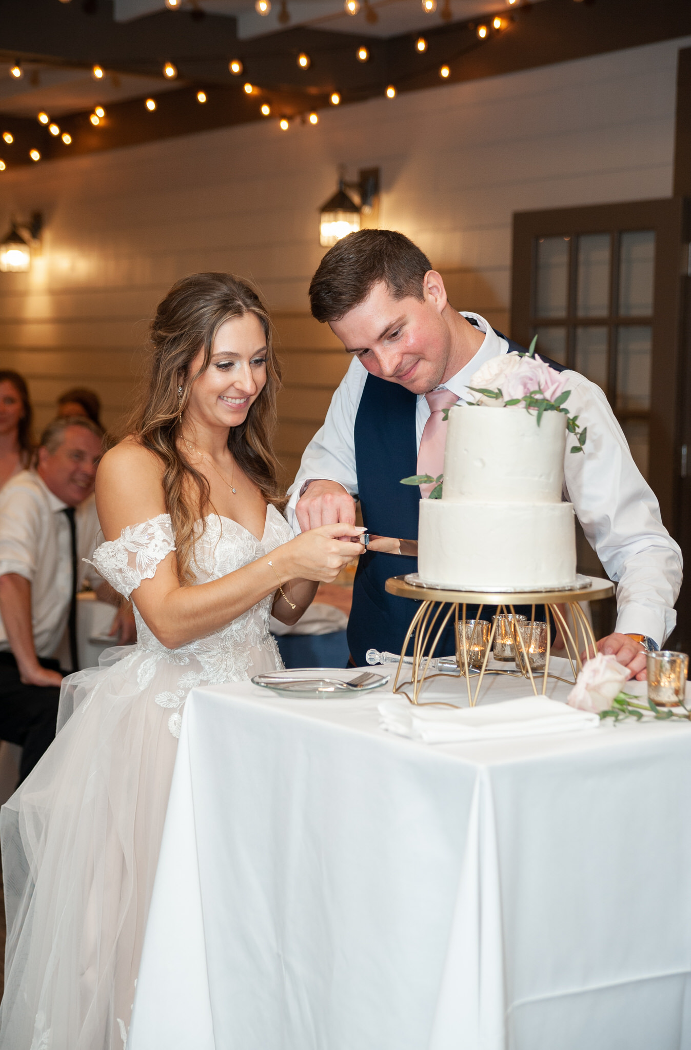 bride and groom cutting into their white wedding cake