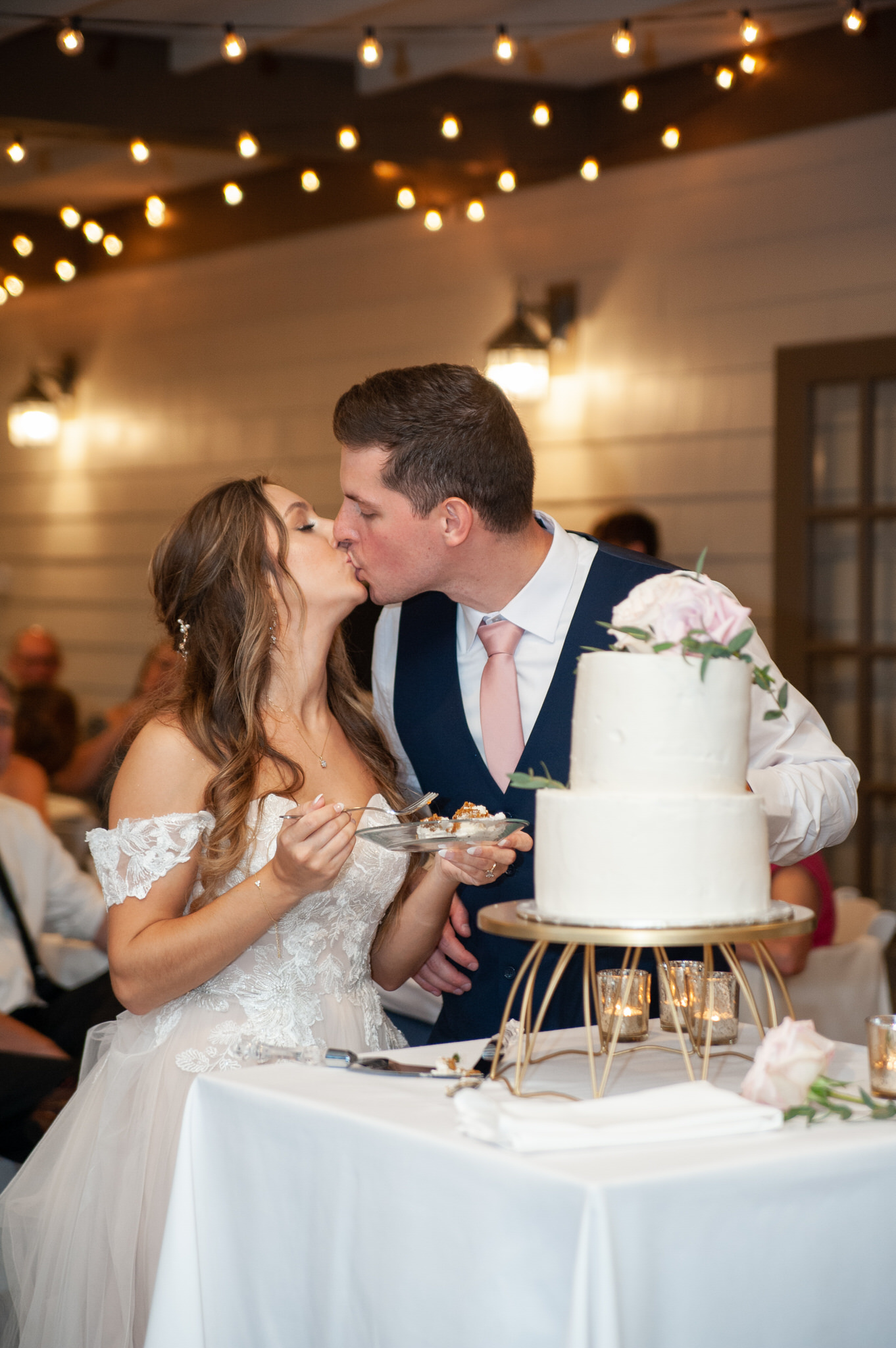 wedding couple kissing while cutting their cake at the Cottage at Ravines