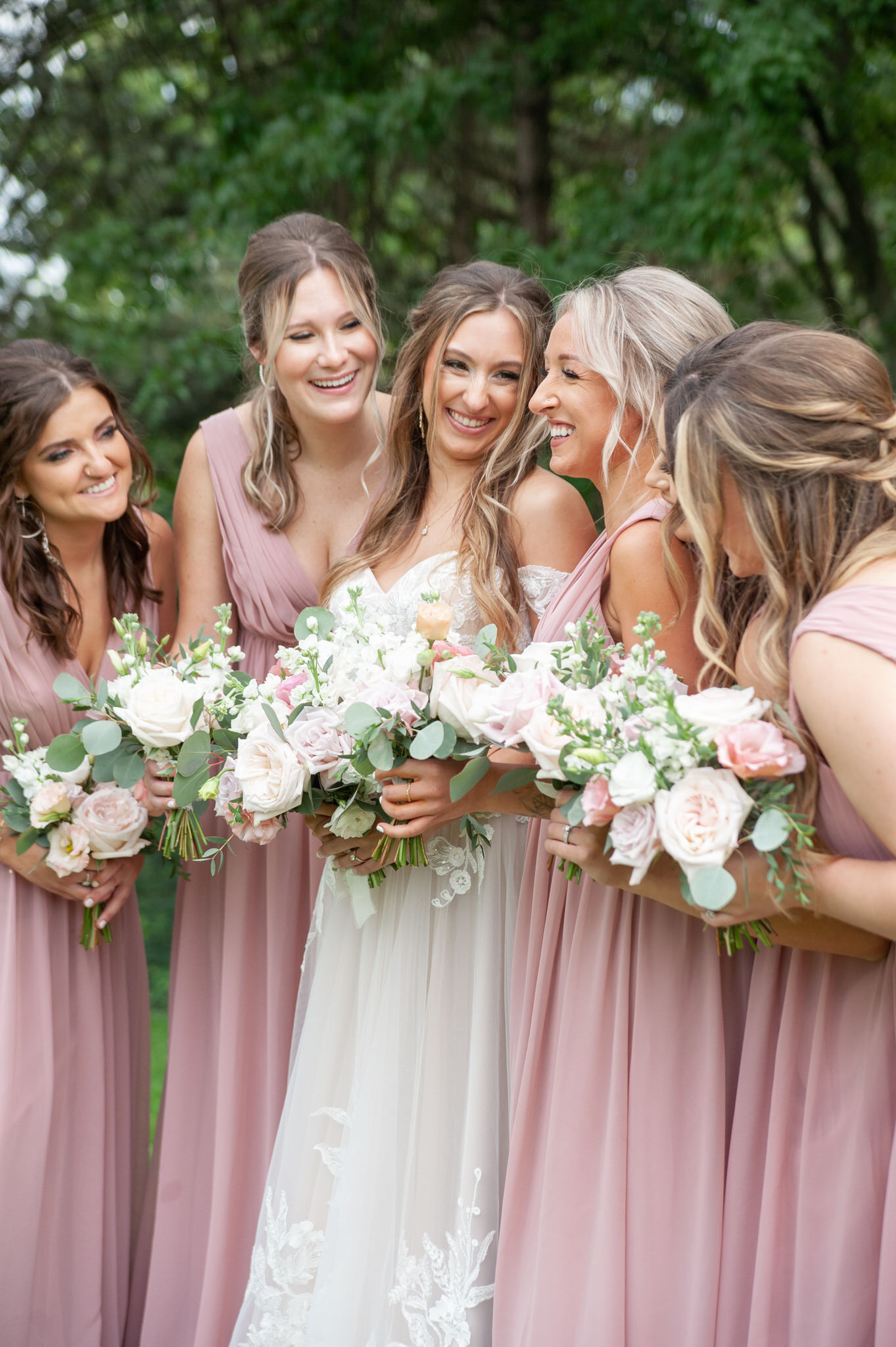 bride smiling at her bridesmaids in blush pink dresses