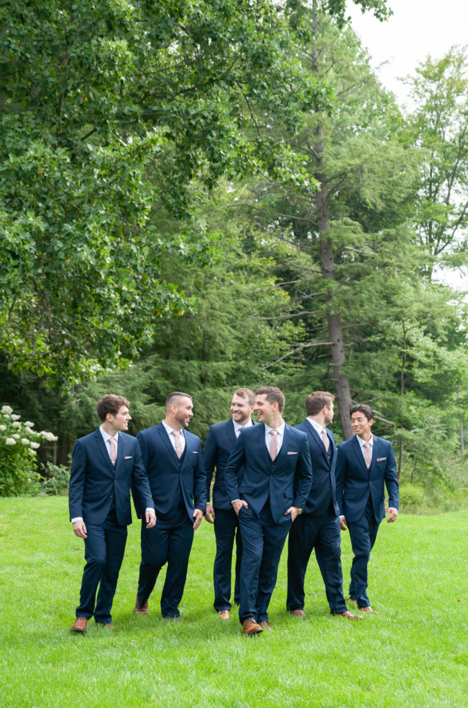 groom and his groomsmen in navy suits walking 
