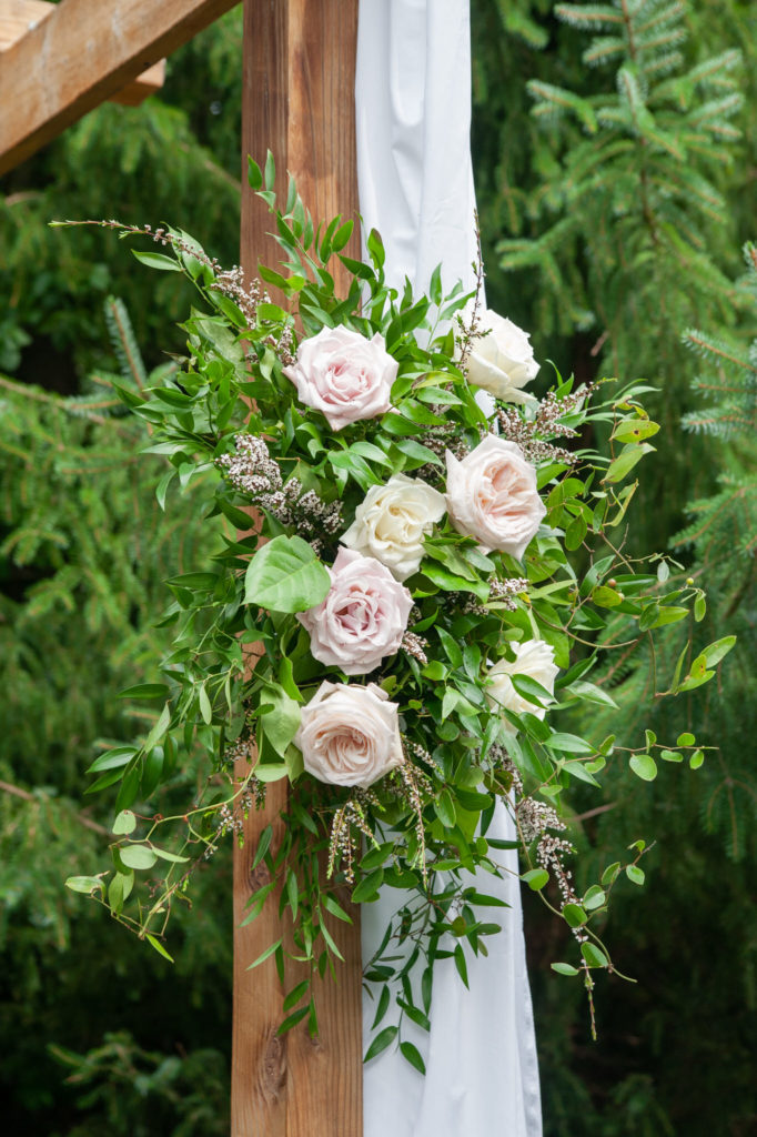 wedding flowers hanging on a wooden ceremony arbor