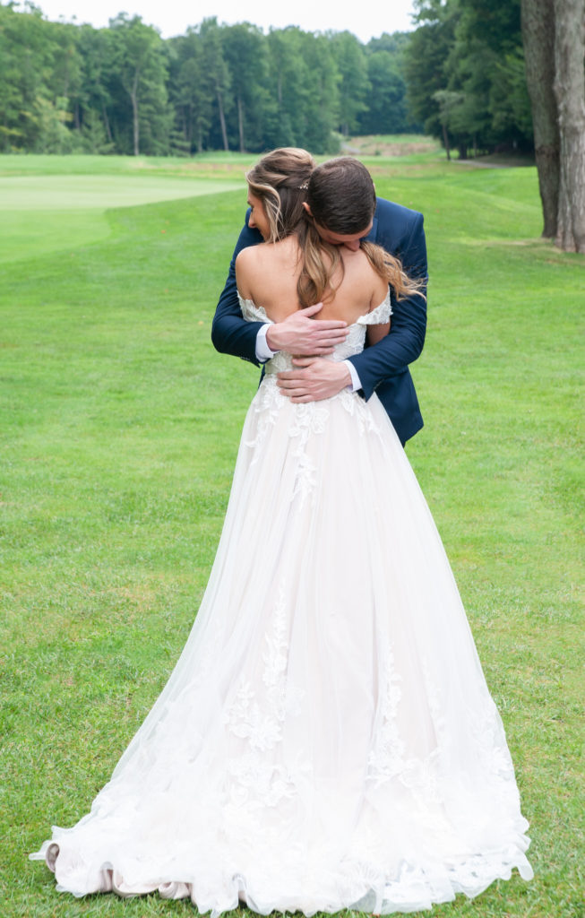 bride and groom embracing on a golf fairway