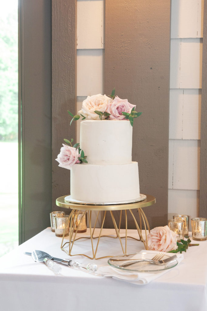 white wedding cake with pink flowers on a gold cake stand