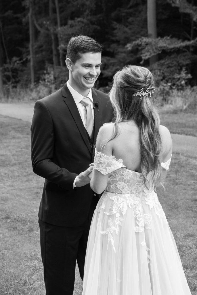 black and white picture of bride and groom holding hands and smiling 