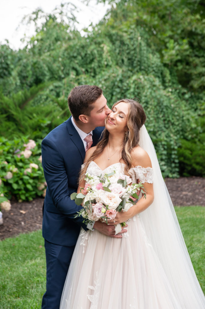 groom kissing his brides cheek at their summer wedding in saugatuck Michigan