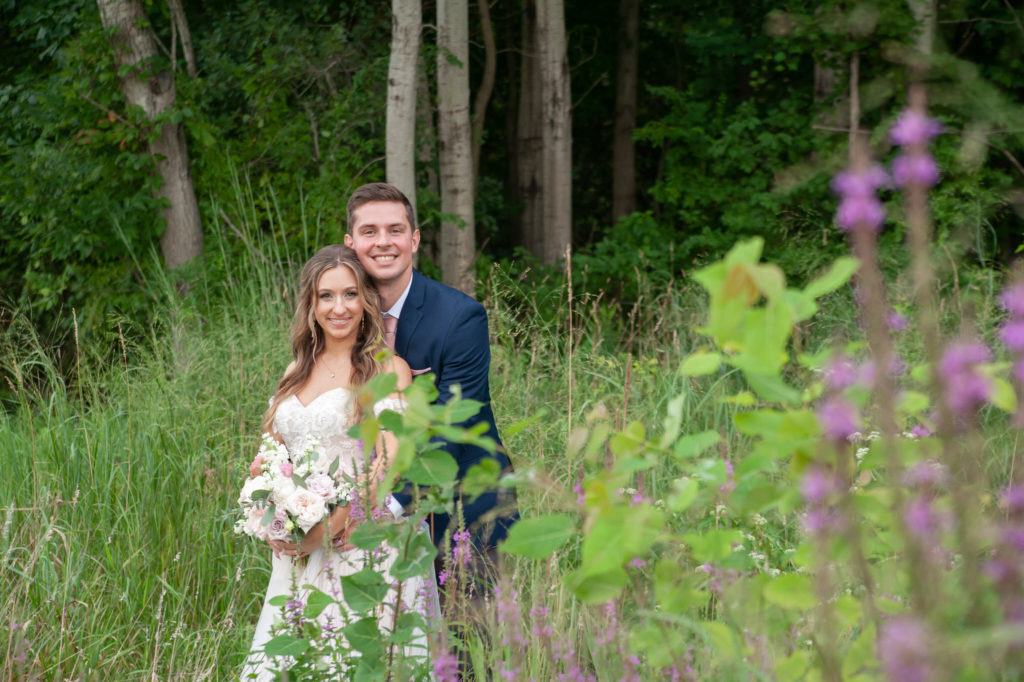 bride and groom smiling while in long grasses