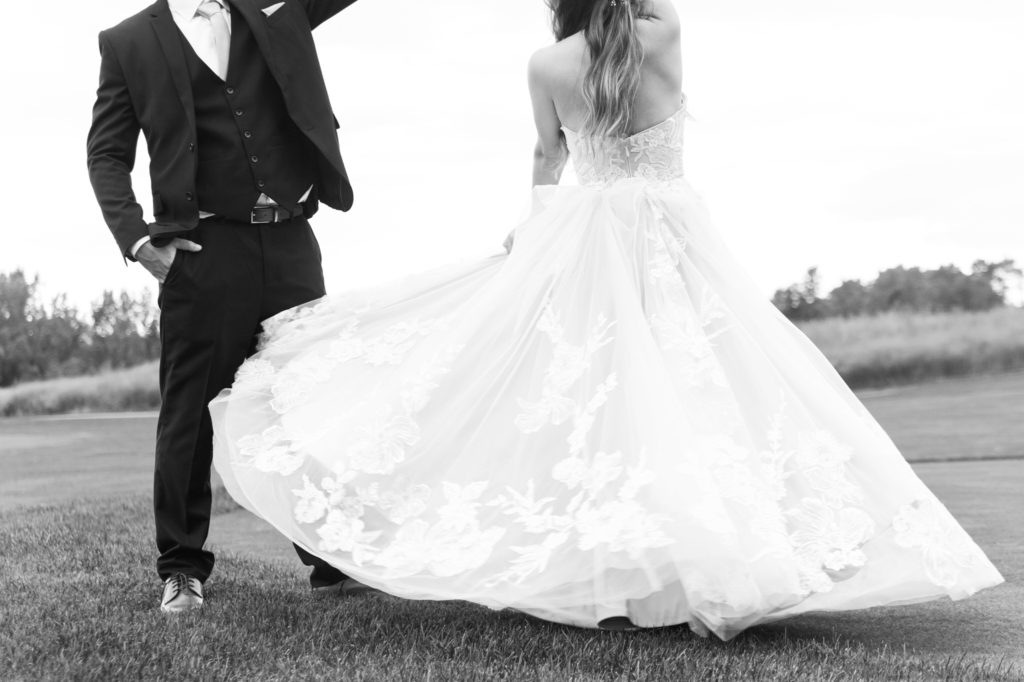 black and white detail of ballgown wedding dress and groom's suit
