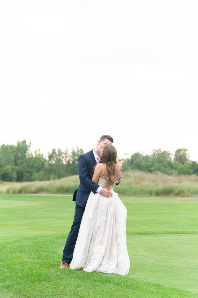 bride and groom kissing at a golf course 