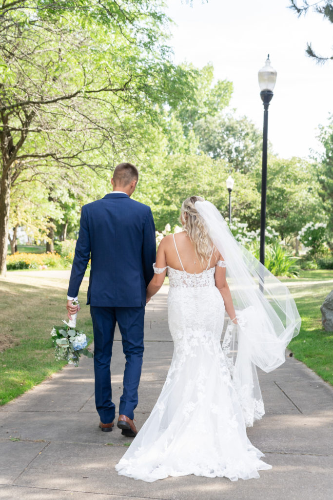 bride and groom walking down a sidewalk after their summer Bay City wedding