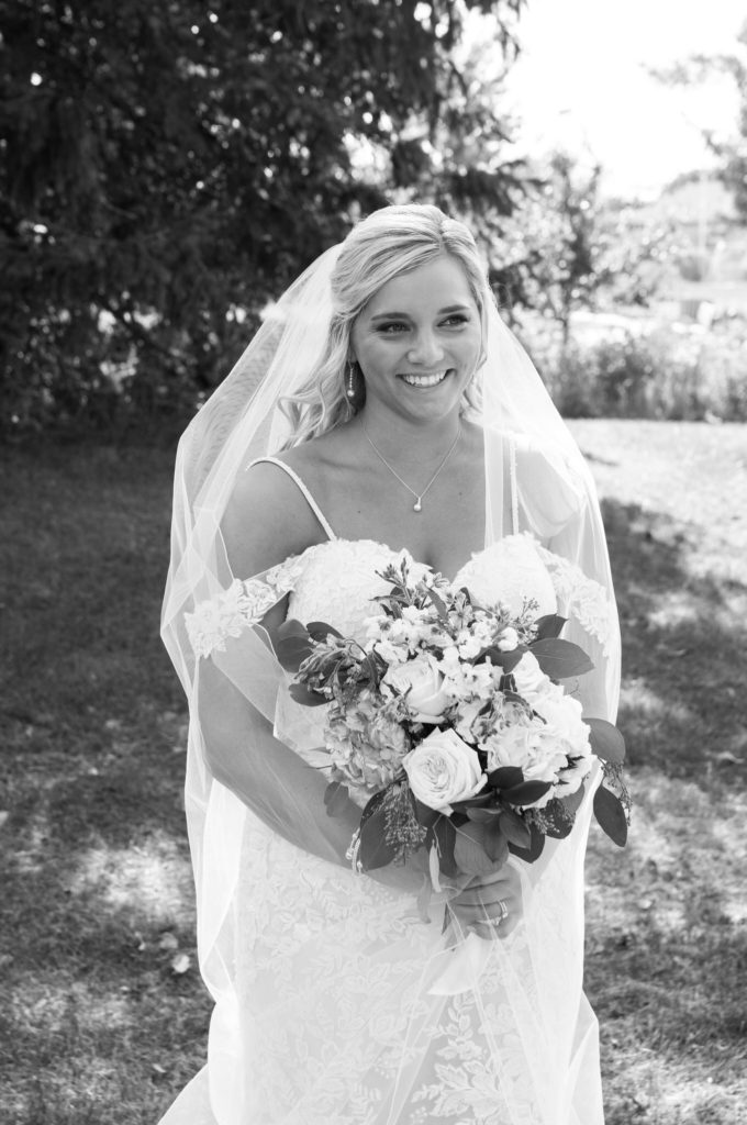 bride smiling away from the camera as she holds her flower bouquet at Veteran's Park in Bay City