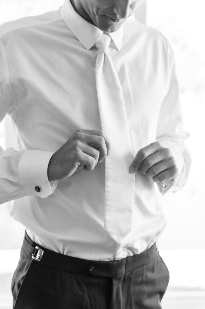 groom adjusting his white tie on his summer wedding day
