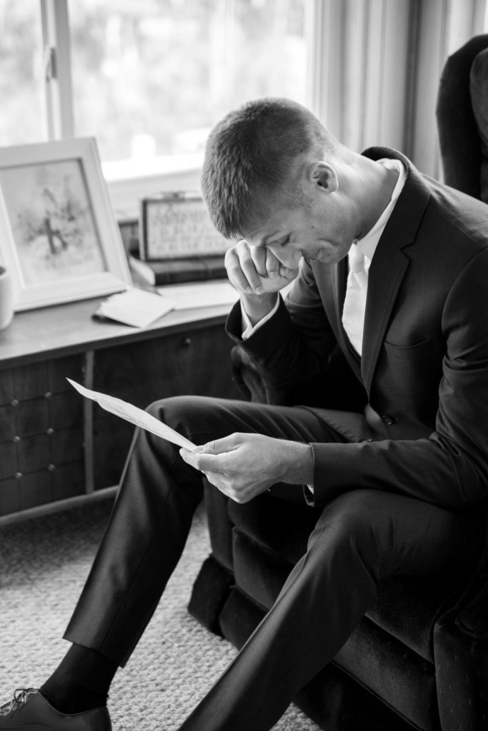 groom getting emotional as he reads a letter from his bride to be