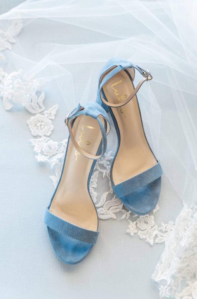 blue LuLu heels on top of a white lace wedding veil and blue styling mat
