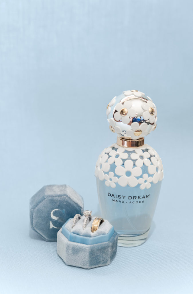 Daisy Dream Marc Jacobs perfume bottle and a blue ring box against a light blue styling mat