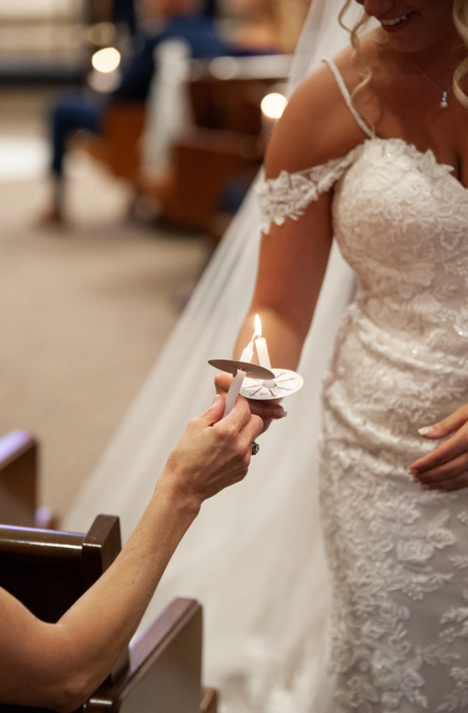 bride lights a wedding candle of one of her guests