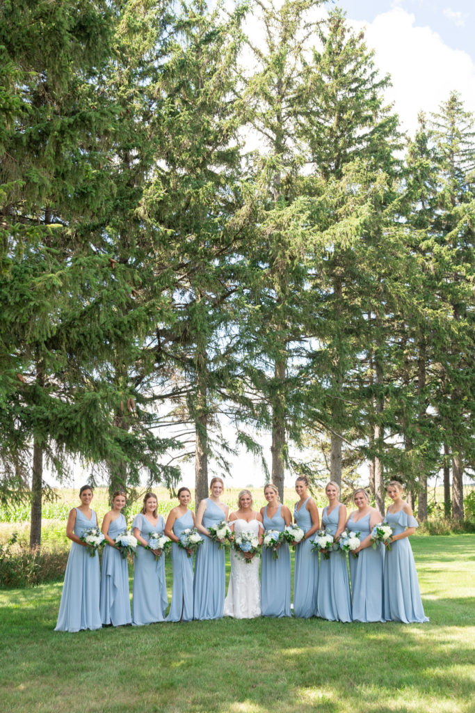 bride with her bridesmaids in light blue with a forest tree-line behind them