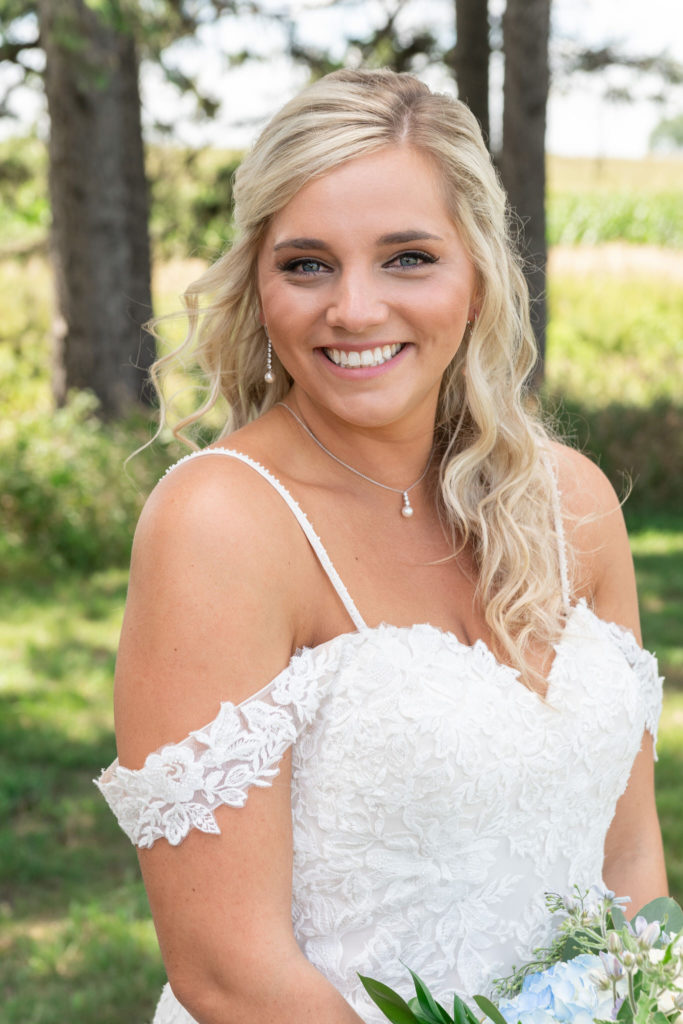 cheerful bride smiles at the camera in her white lace wedding dress on her summer wedding in Bay City
