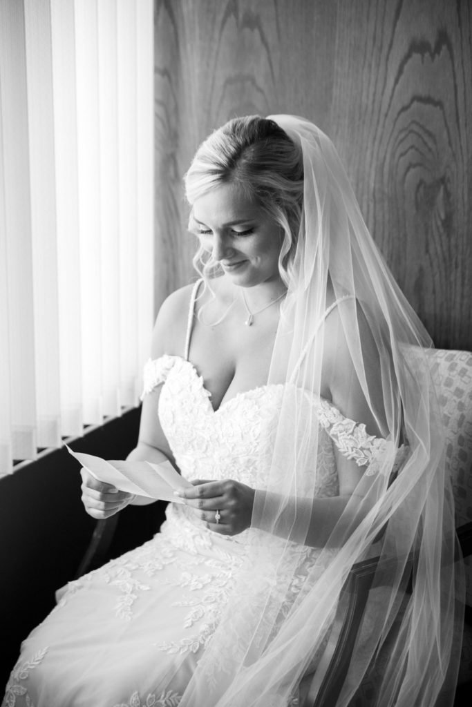bride reads a letter from her groom beside a window