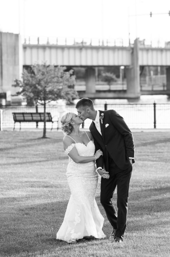 bride and groom kissing and holding hands in front of the Bay City river