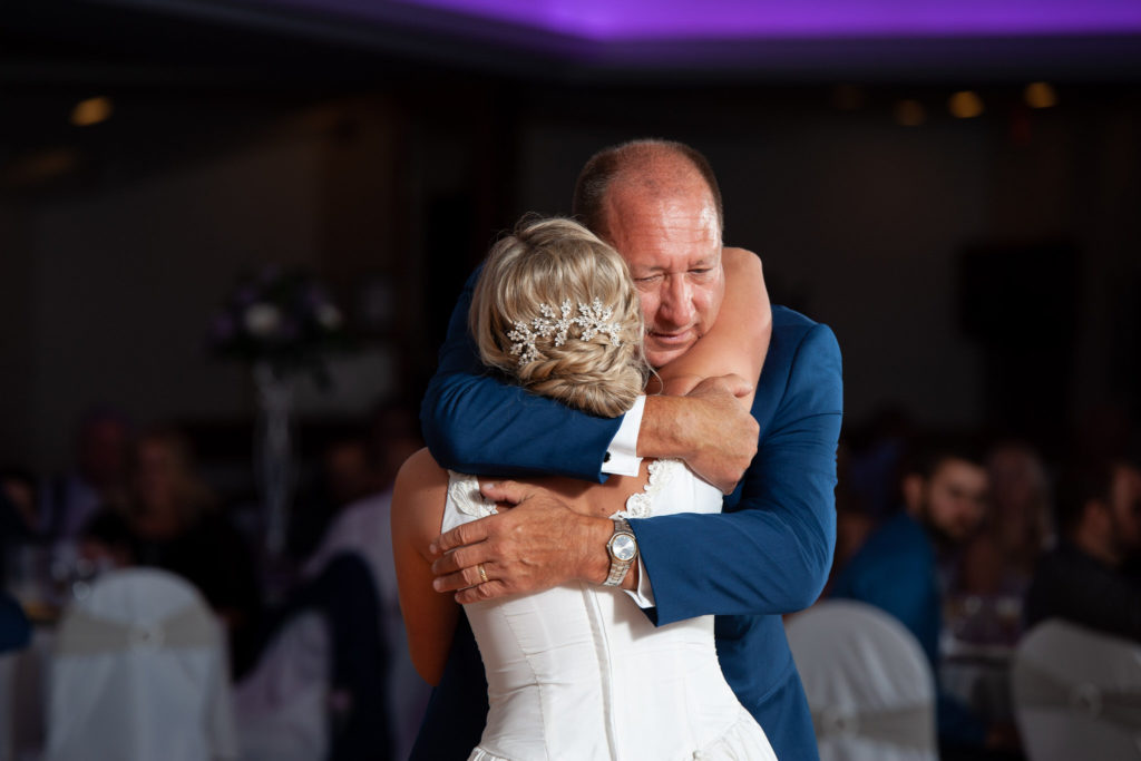 father of the bride hugs his daughter after sharing their first dance together