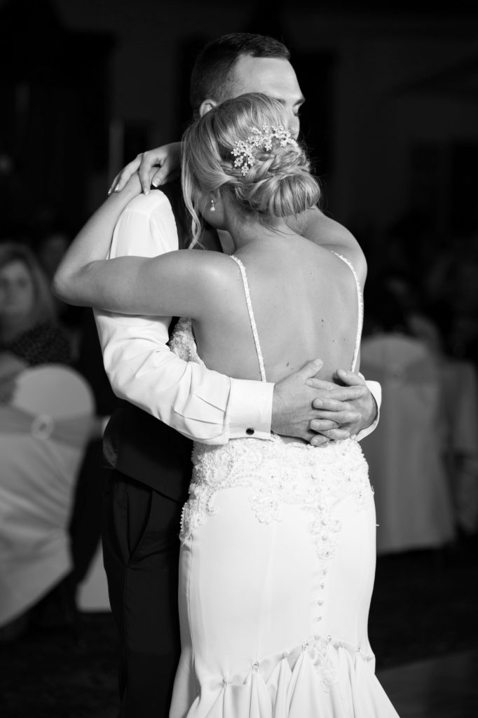 groom hugs his bride and gently dances with her during their first dance at their wedding reception