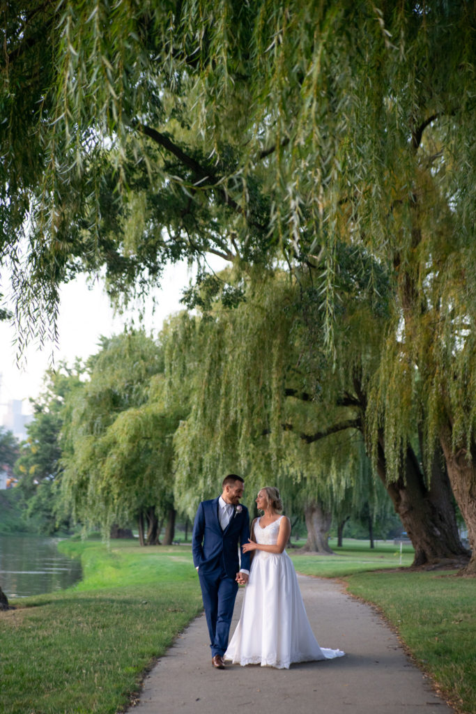 bride and groom walking hand in hand down a paved pathway at sunset during their Frankenmuth wedding