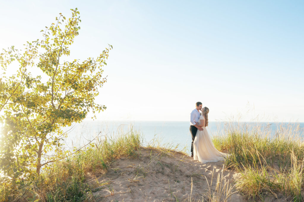 Sunset elopement at Lake Bluff Preserve. Couple in wedding attire standing on a sandy cliff.