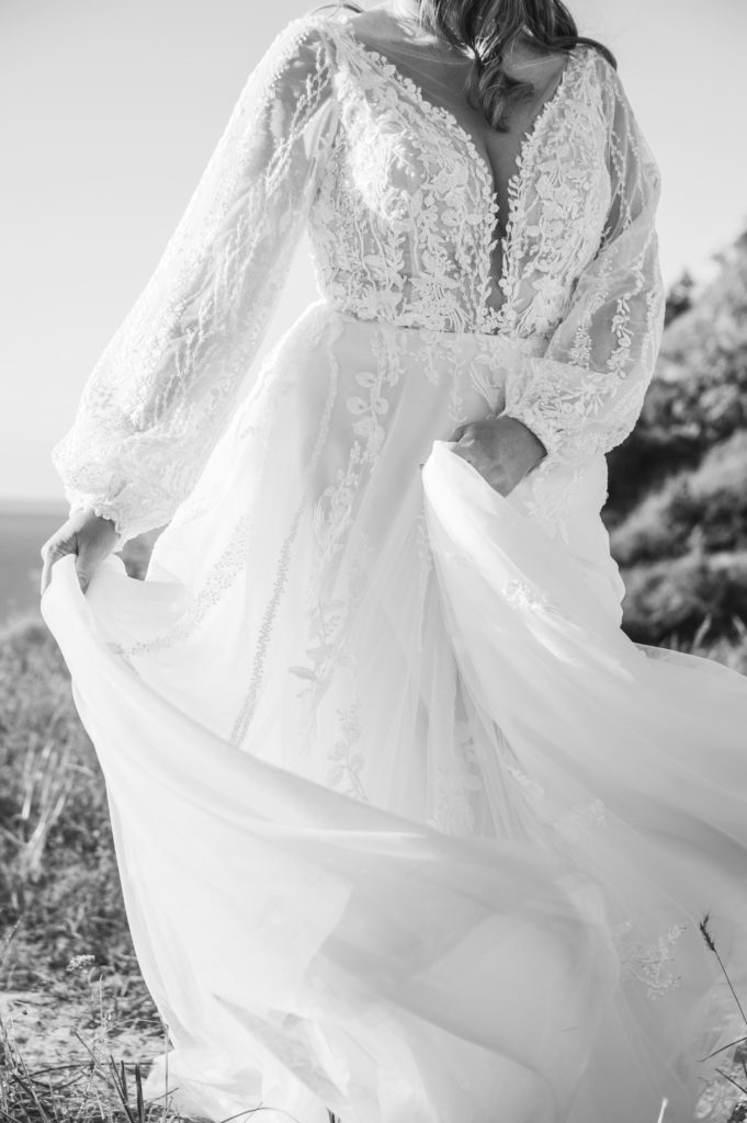 A bride plays with her long sleeve flowing dress for a solo portrait after her northern Michigan elopement.