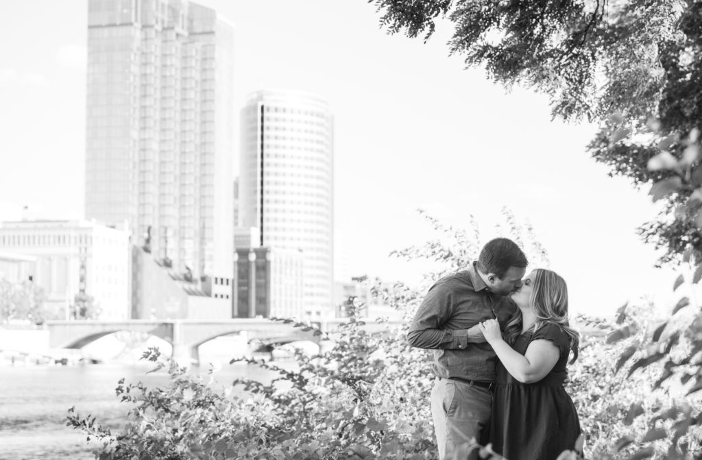 couple kisses with the Grand Rapids city skyline in the background