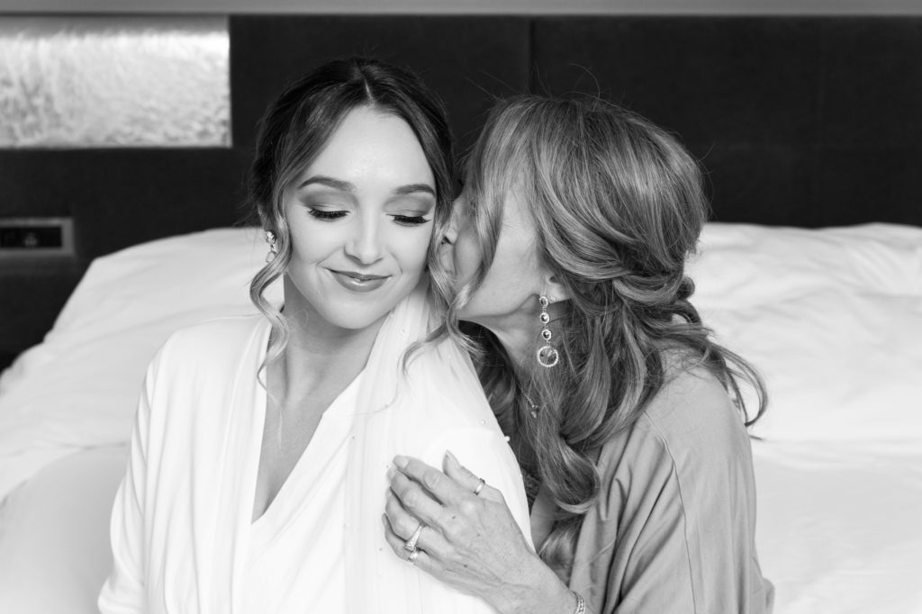 mother of the bride kisses her daughter on the cheek before her wedding day at The Baronette Renaissance Detroit-Novi Hotel