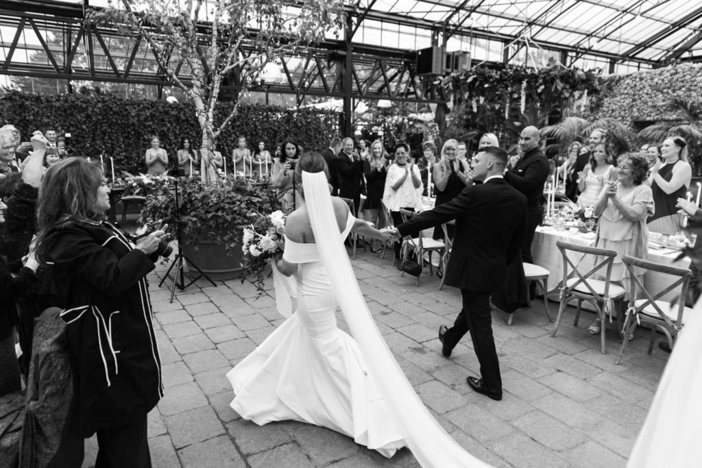 bride and groom make their grand entrance at their greenhouse wedding reception
