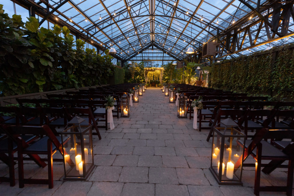 a romantic lit wedding ceremony at night at Planterra Conservatory in West Bloomfield, Michigan