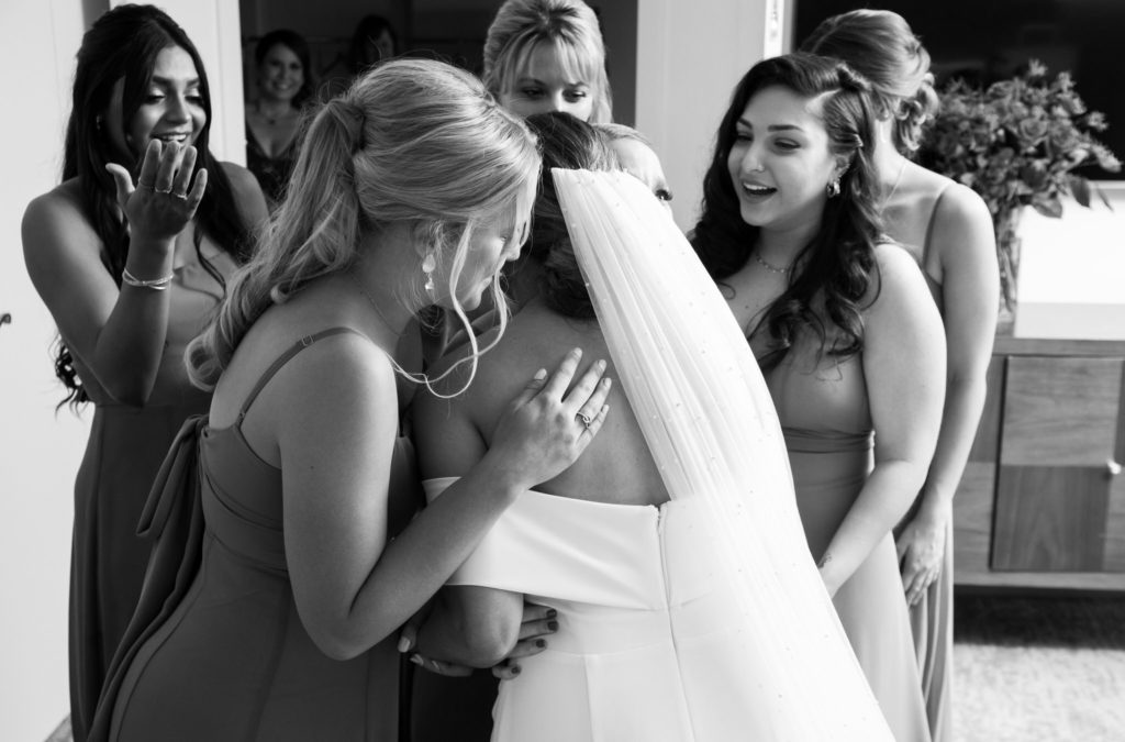 bridesmaids circle around the bride and hug her before her wedding in West Bloomfield, MI