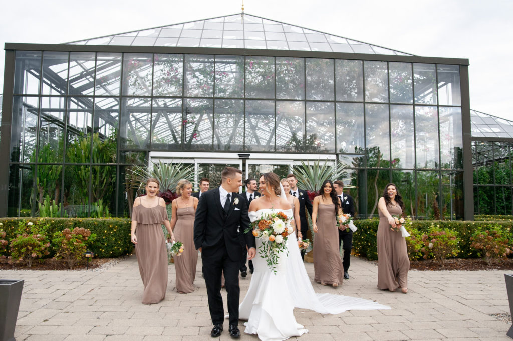 a wedding party walking in front of the Planterra Conservatory in West Bloomfield
