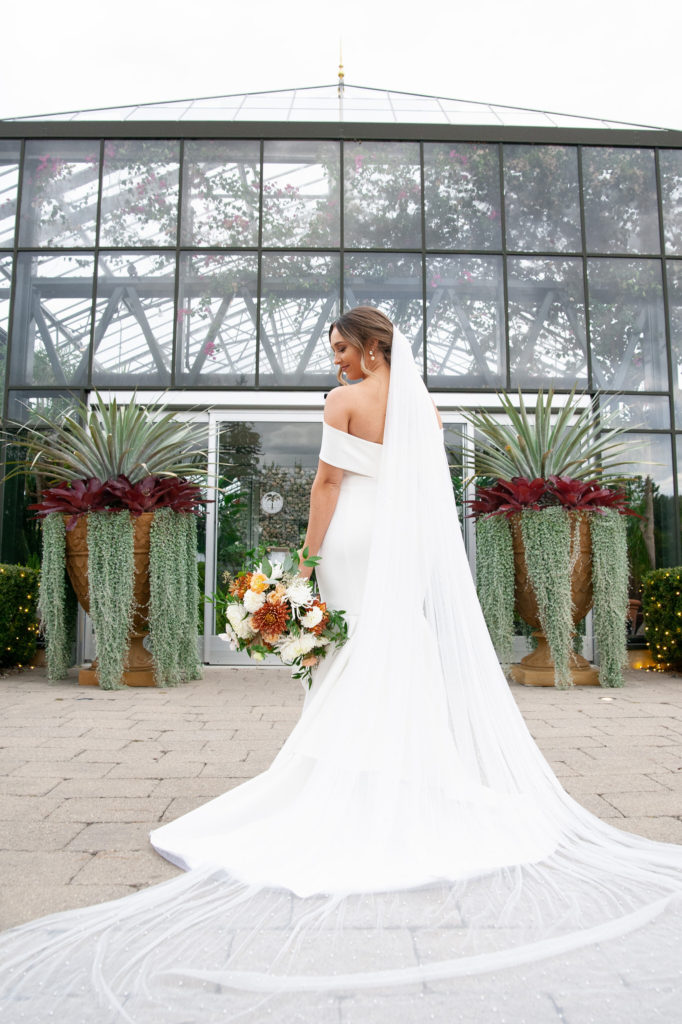 bride poses for a photo outside the botanical Planterra Conservatory greenhouse wedding venue